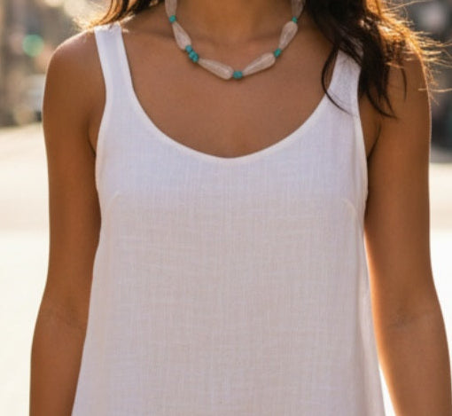Person wearing a white tank top with a blurred background