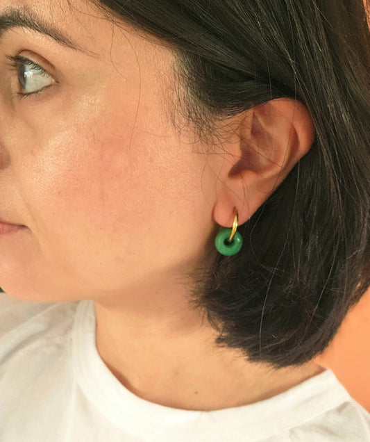 Close-up of a person wearing a green earring with a neutral background