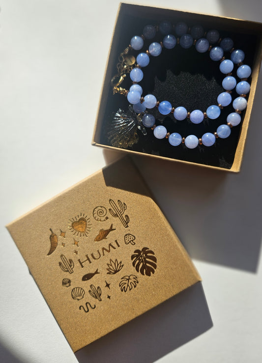 Blue beaded bracelet in a box with a HUMI branded box on a light background
