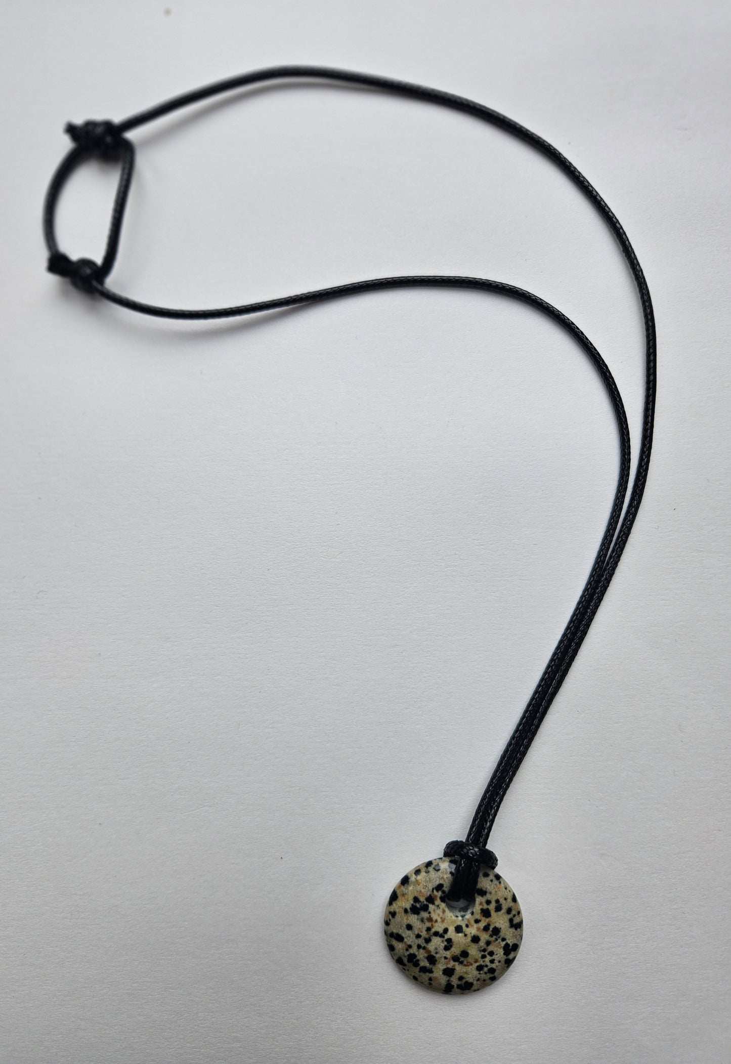 Necklace with a round, spotted pendant on a light gray background