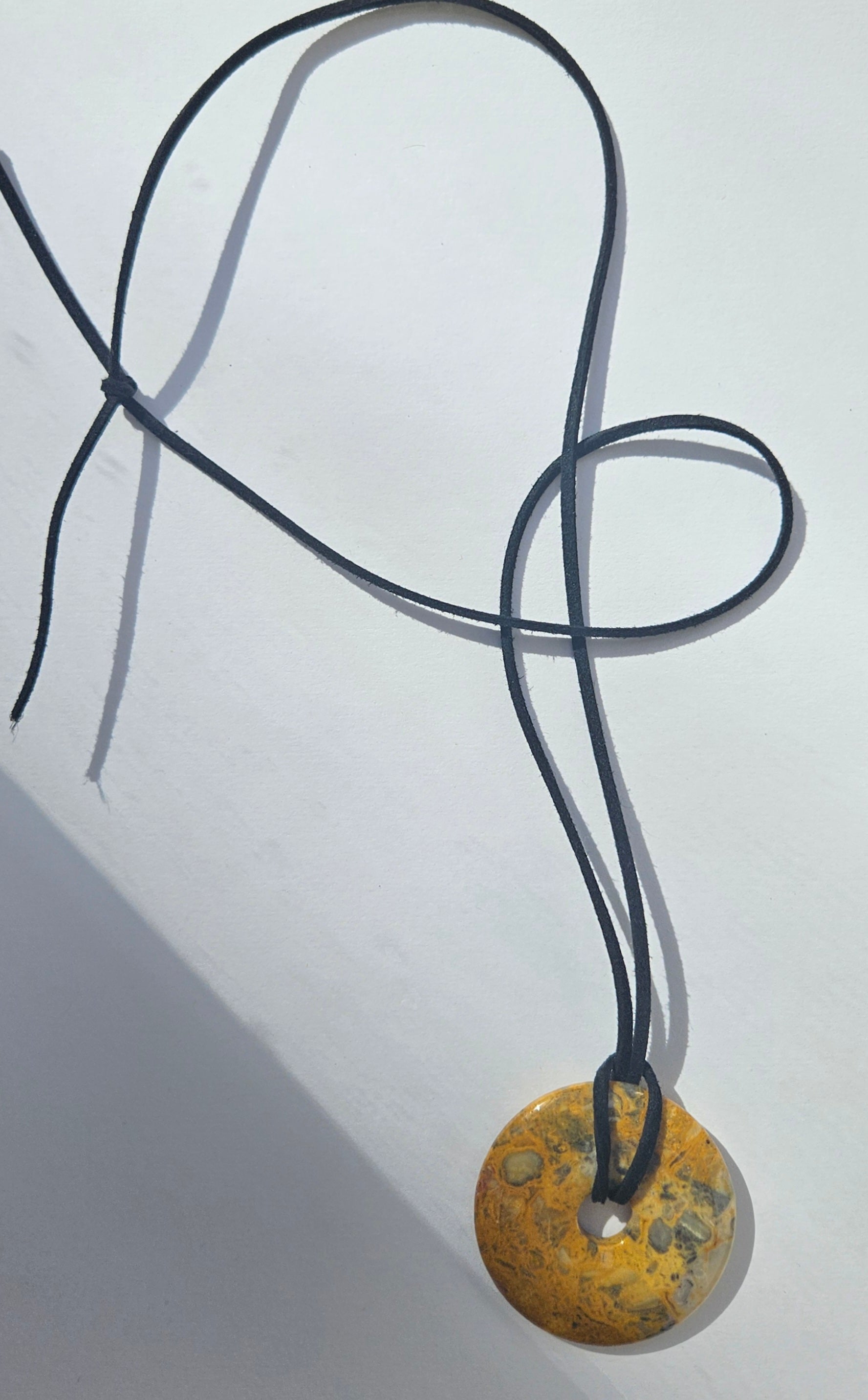 Necklace with a round, textured pendant on a light gray background