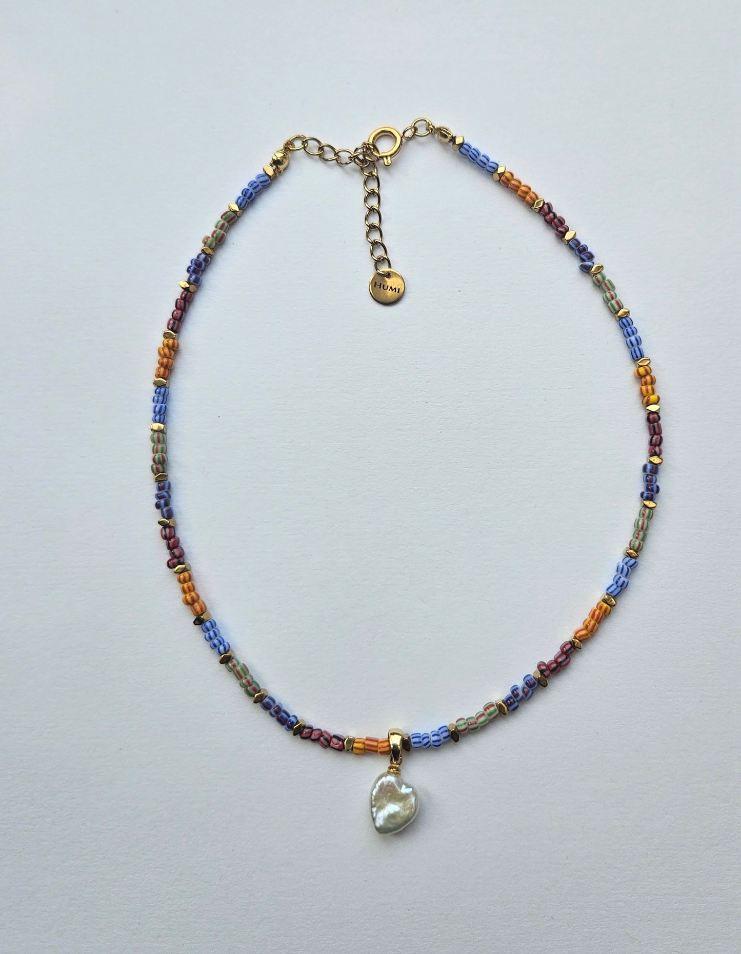 Multicolored beaded necklace with a heart pendant on a light gray background
