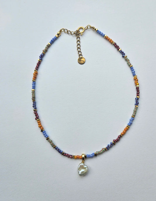 Multicolored beaded necklace with a heart pendant on a light gray background