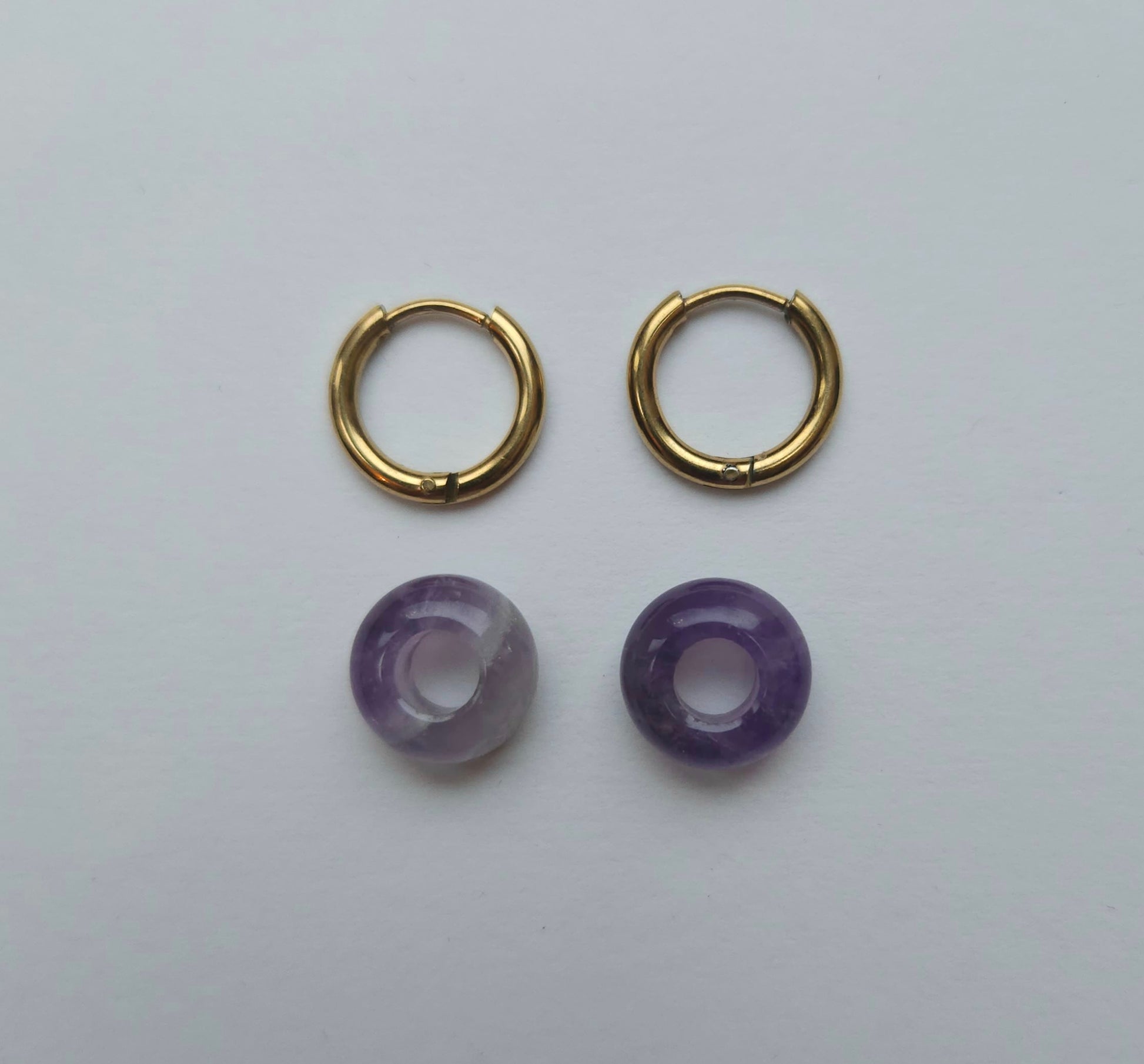 Gold hoop earrings with purple beads on a white background