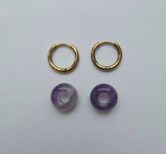 Gold hoop earrings with purple beads on a white background
