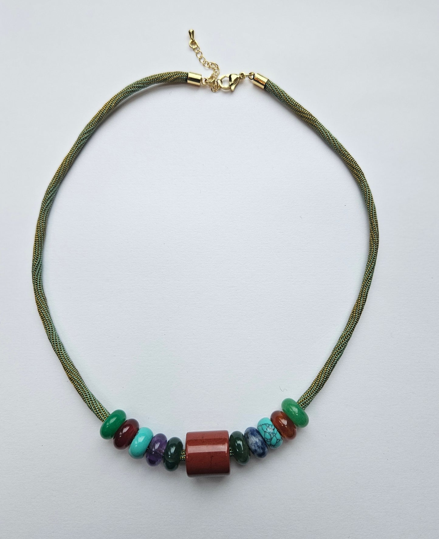 Necklace with green cord and multicolored beads on a light gray background