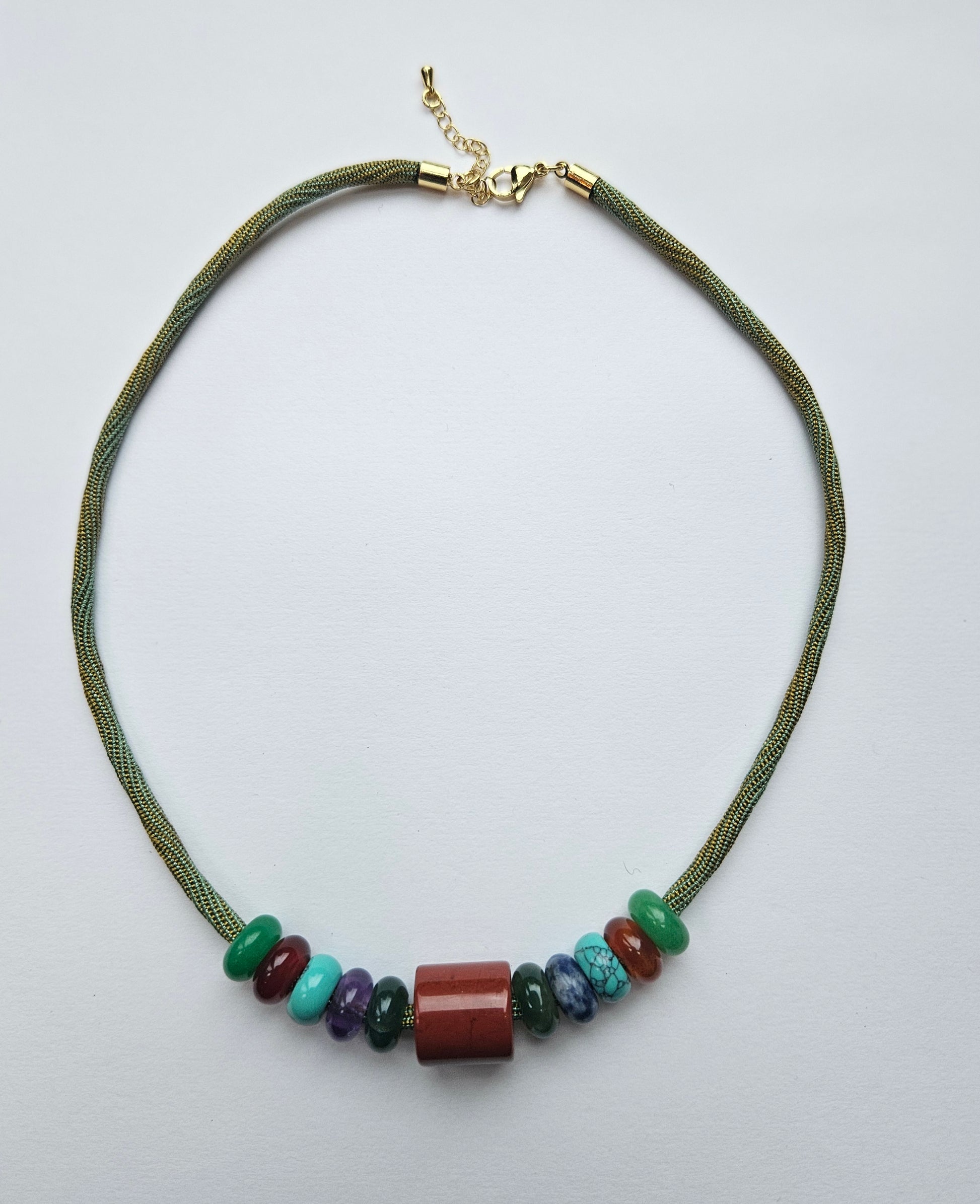 Necklace with green cord and multicolored beads on a light gray background