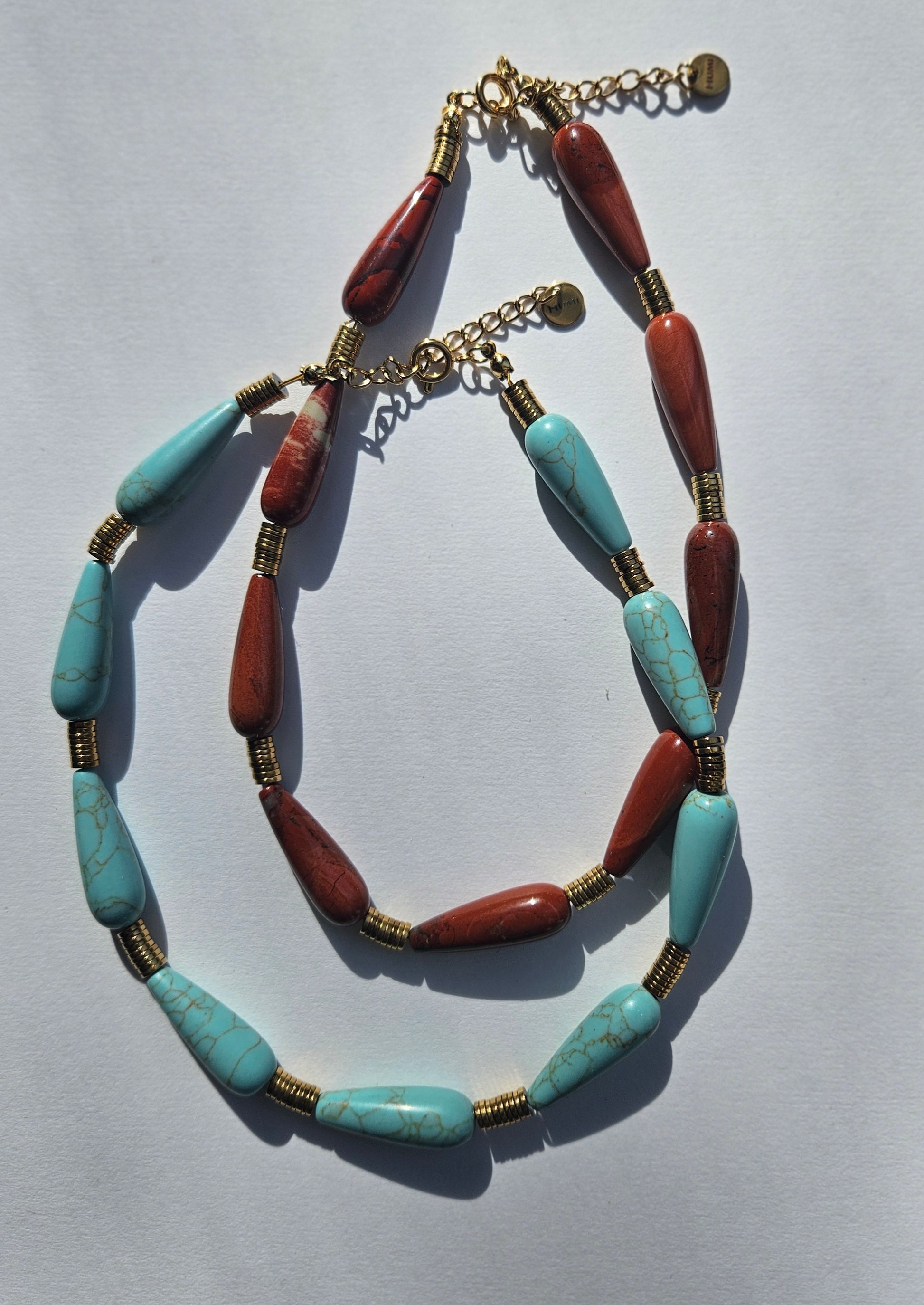 2 necklaces. One is turquoise, the other red jasper.