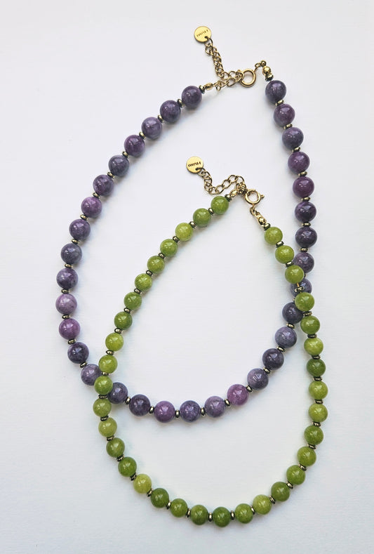 Two beaded necklaces, one purple and one green, on a white background