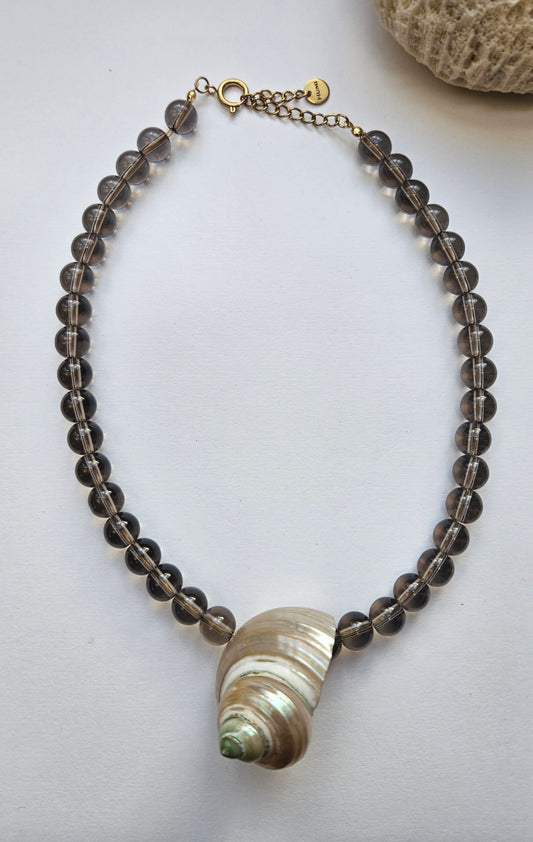 Necklace with beads and a shell pendant on a light background