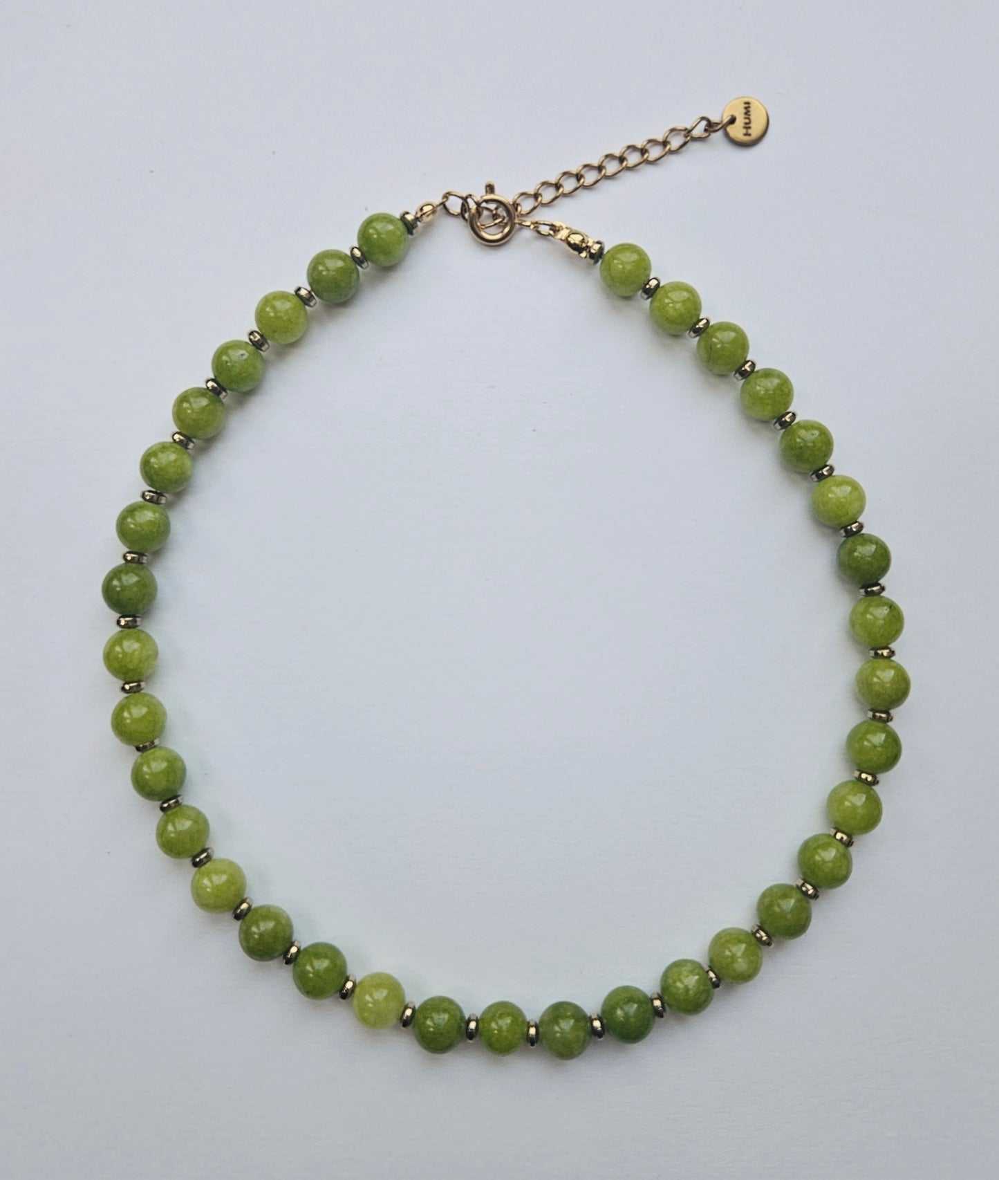 Green beaded necklace on a light gray background
