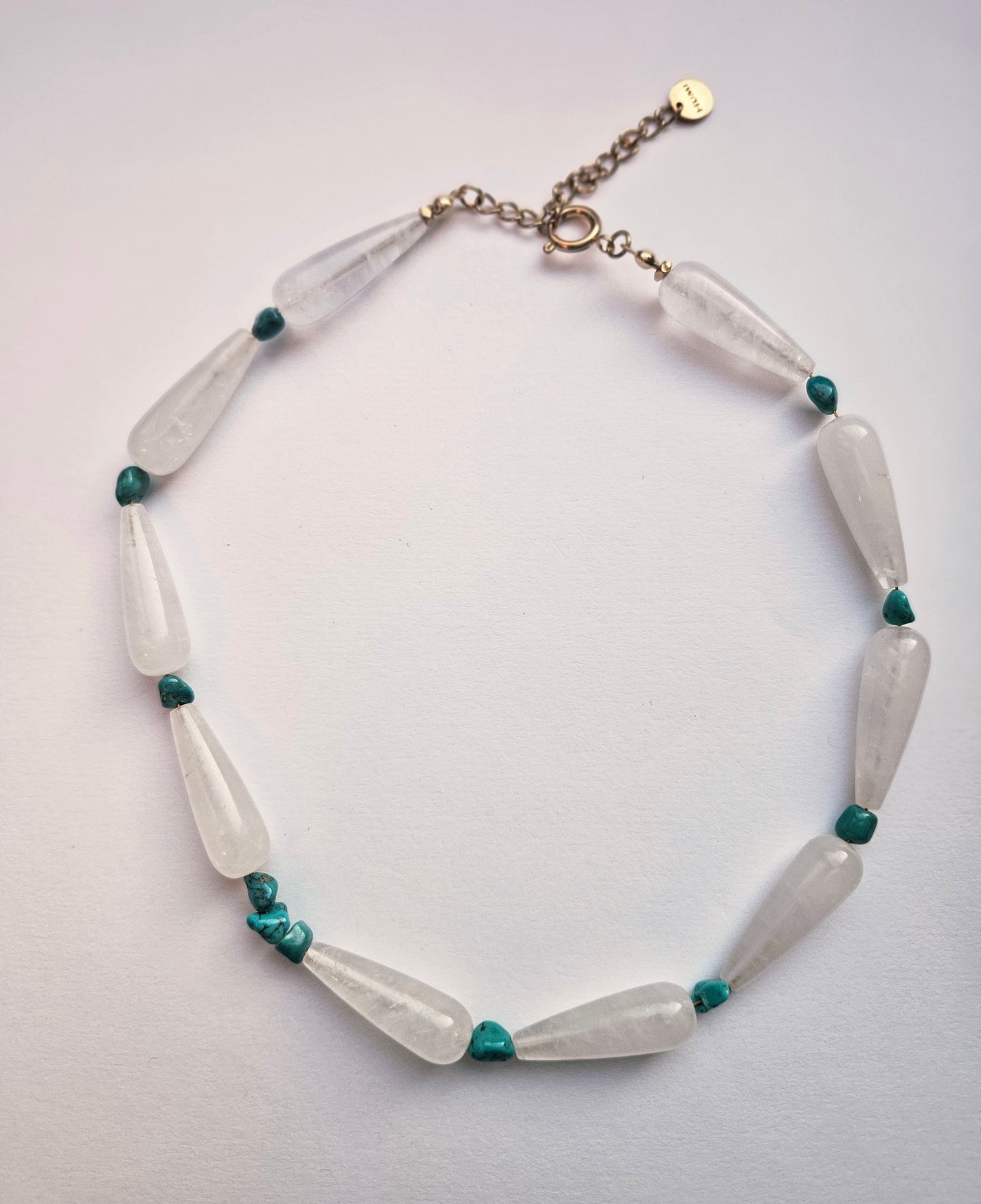 Necklace with white and green beads on a light gray background