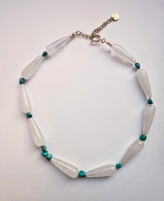 Necklace with white and green beads on a light gray background
