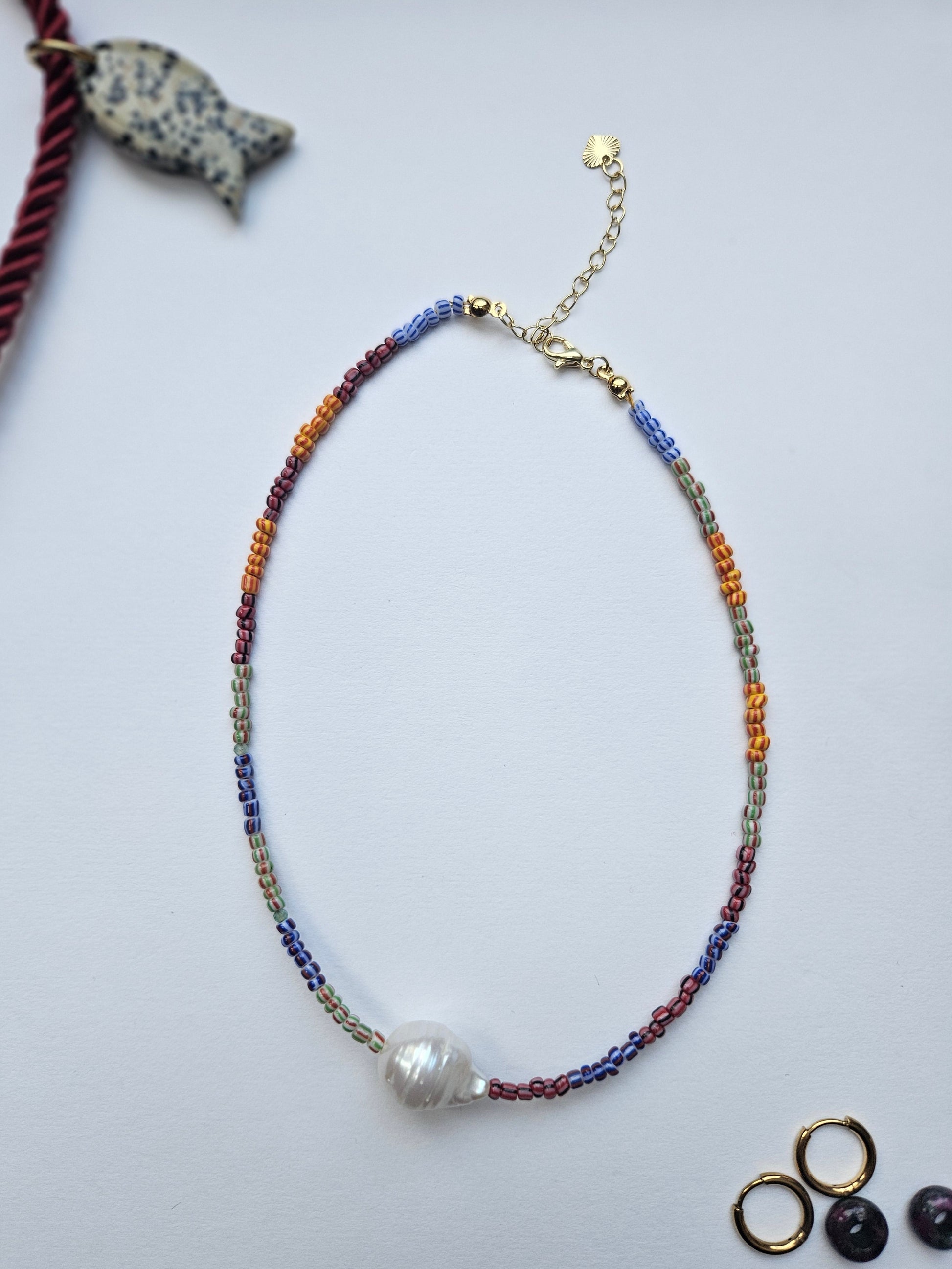 Colorful beaded necklace with a pearl pendant on a light gray background