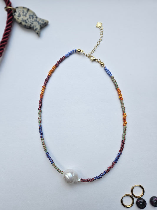 Colorful beaded necklace with a pearl pendant on a light gray background
